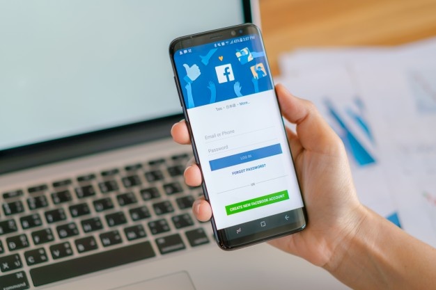 hand holding samsung s8 with mobile application for facebook on the screen