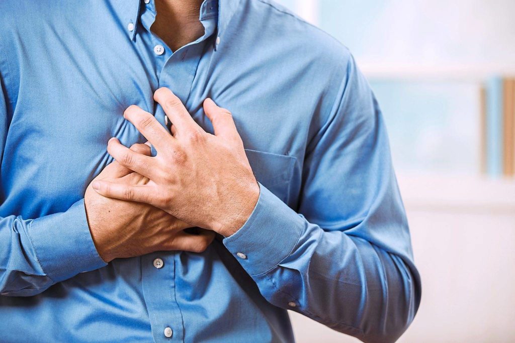man presses his chest because of a heart attack