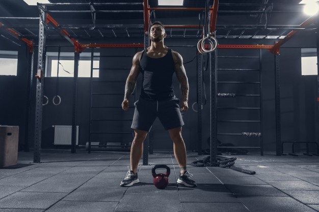 young muscular caucasian athlete practicing squats in gym with the weight