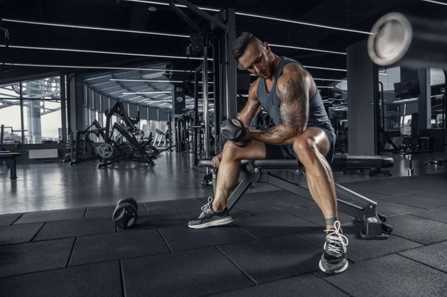 young muscular caucasian athlete practicing in gym with the weights.