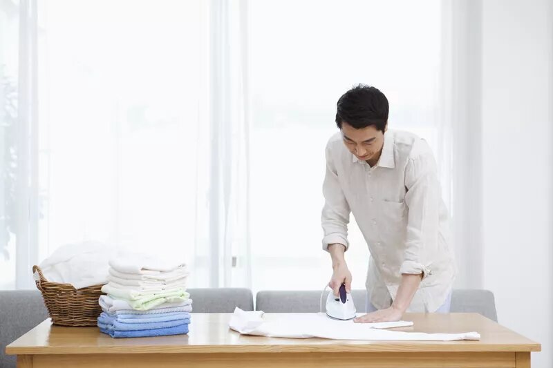 man ironing clothes on table