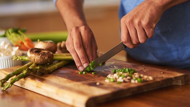hands cutting vegetables on board