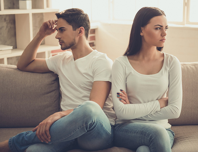 Couple is having a quarrel while sitting on sofa at home