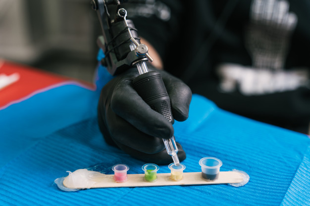 a tattoo artist mixing colors in a plastic cup