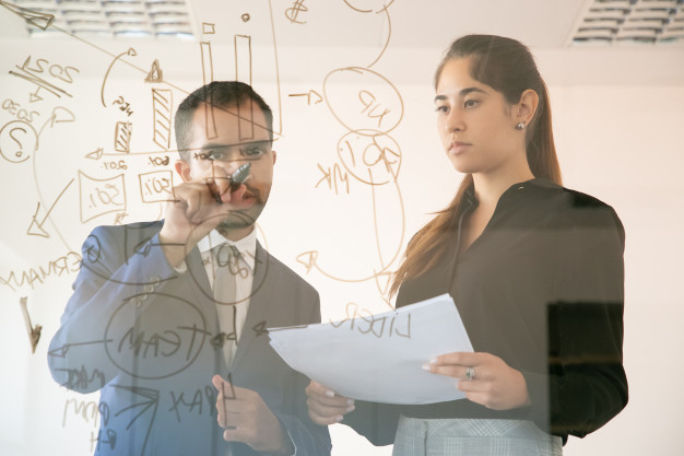 american manager writing chart on glass board