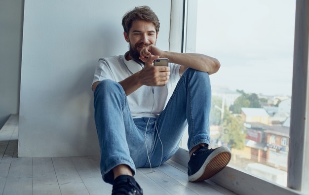 A man sits on a windowsill with a phone