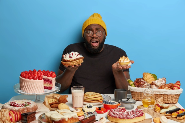 man holds two tasty cakes, cannot make choice what to eat,