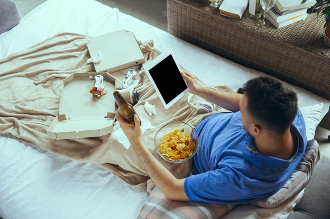 Lazy man living the whole life in his bed surrounded with messy 