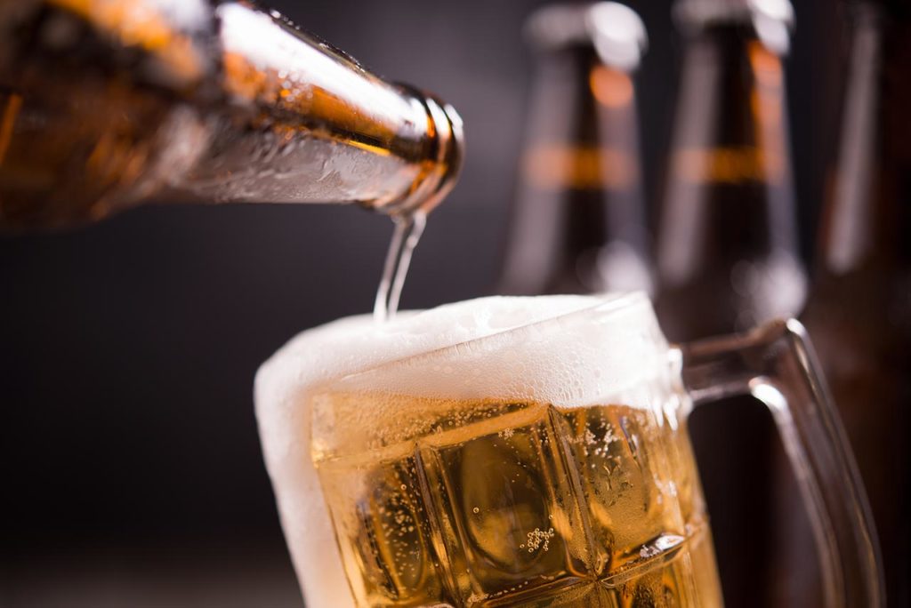Glass bottles of beer with glass and ice