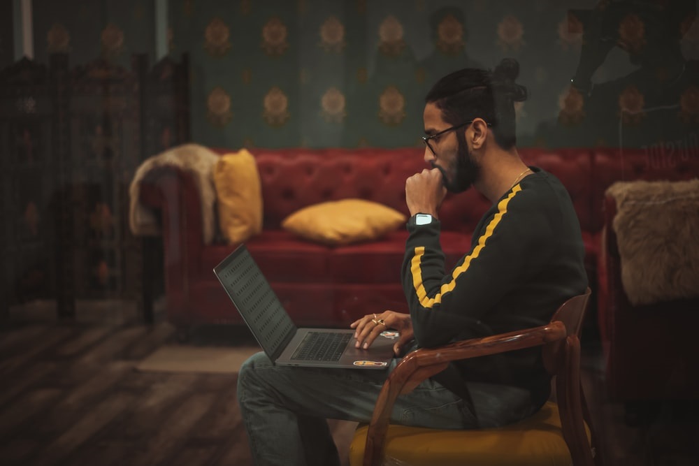  man sitting at his desk and looking at a laptop