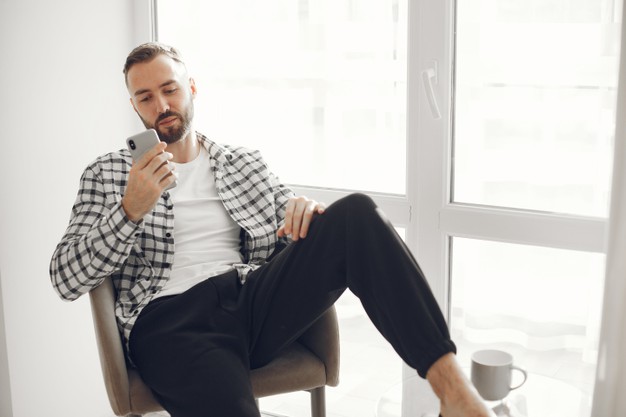 man relaxing at home with smartphone