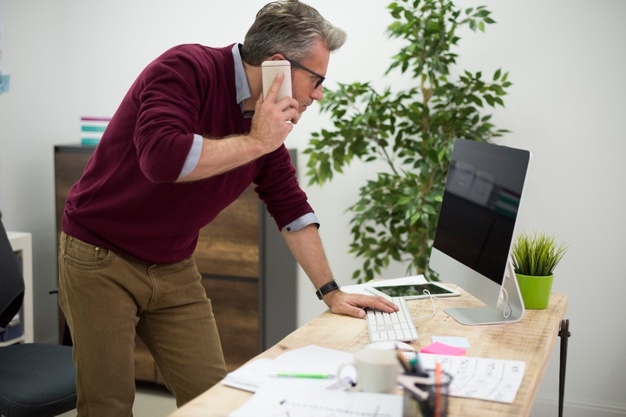 Working man bending over the desk 