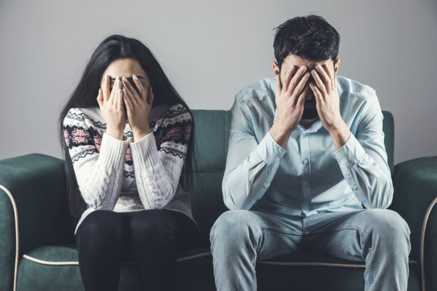 sad couple sitting on sofa