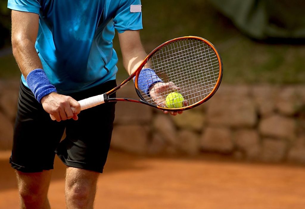 a tennis player prepares to serve a tennis ball