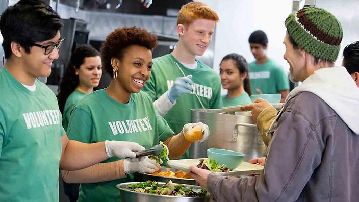 Volunteers serving food to poor people