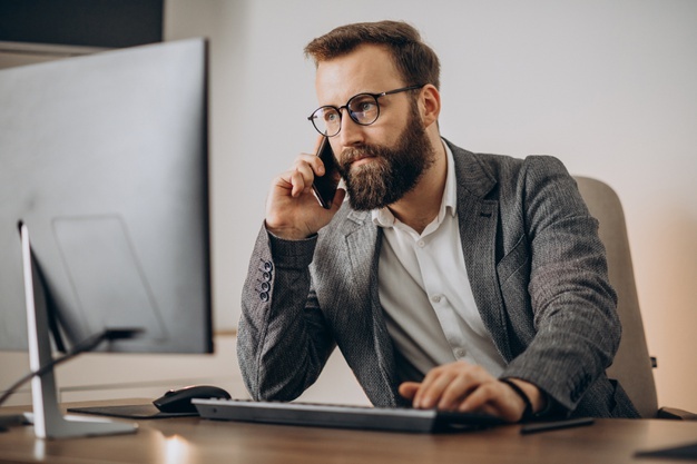 man talking on phone and working on computer