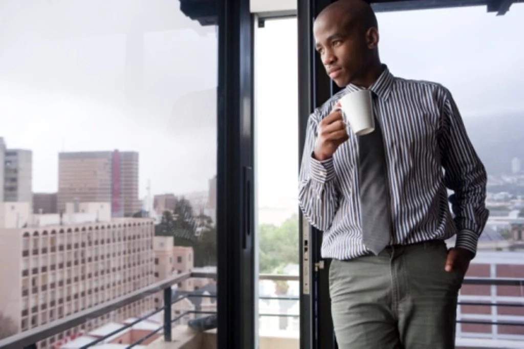 businessman looks out the large window of his office