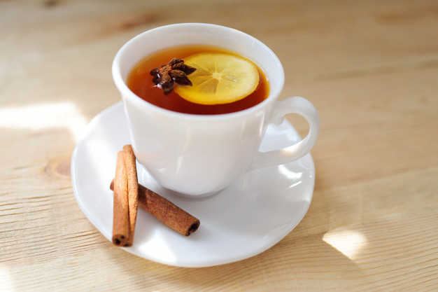 Cup of warm hot lemon drink with lemon slice on wooden
