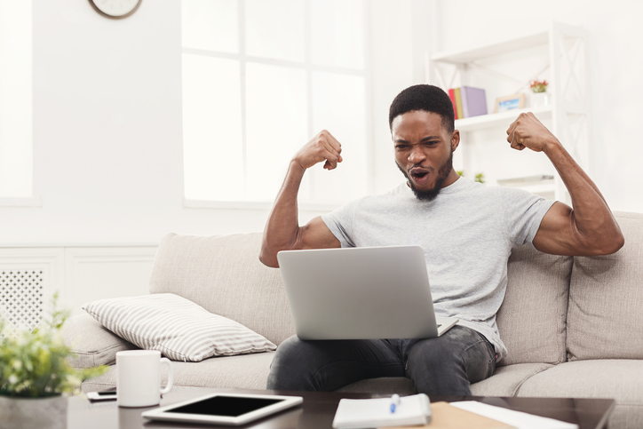  Cheerful young man in casual wear keeping arms raised 
