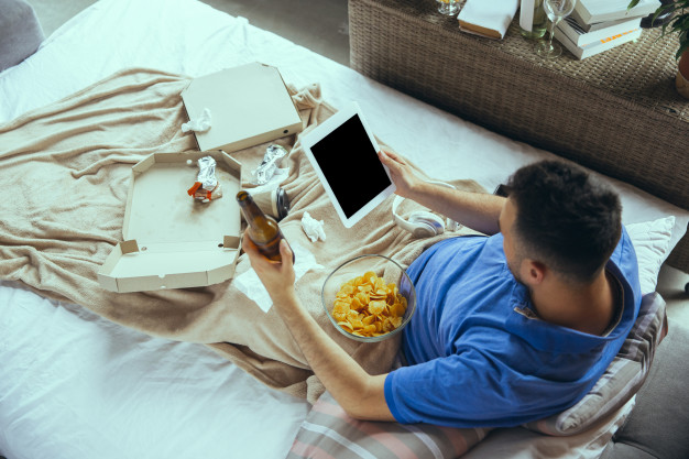 Lazy man living the whole life in his bed surrounded with messy