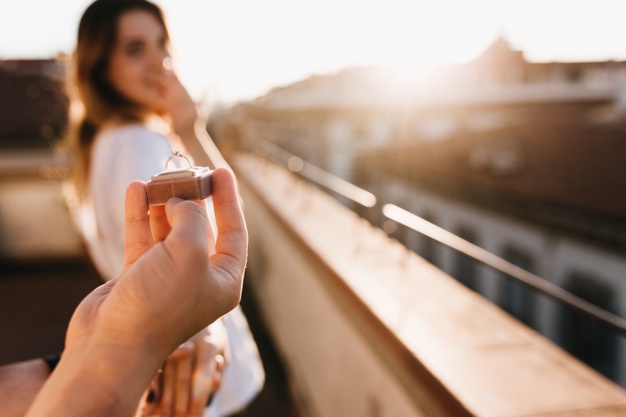 Man makes offer of marriage to girl standing on the roof on a sunny