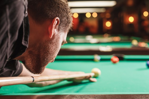 Man trying to hit the ball in billiard