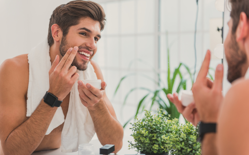 smiley man applying cream on his face