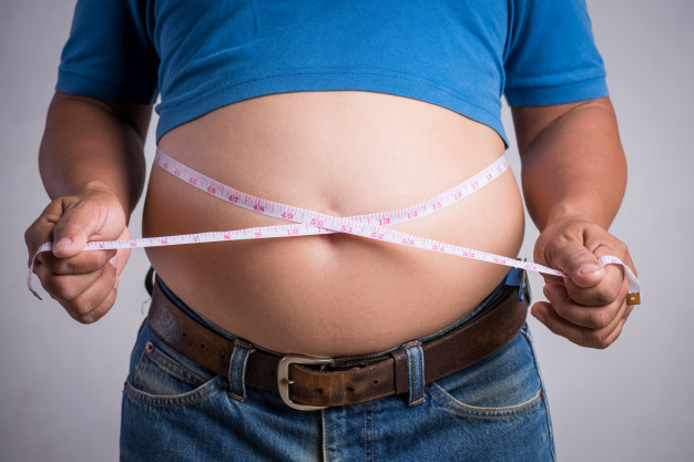 Overweight or fat adult man in very tight jeans with measuring tape