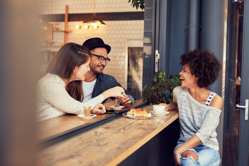 young people sitting together at a cafe having some food and coffee. Group of friends meeting in a coffee shop