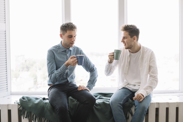 Young male friends having morning breakfast at home 