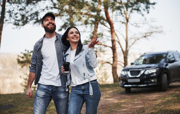 Beauty of the nature. couple have arrived to the forest on their brand new black car 