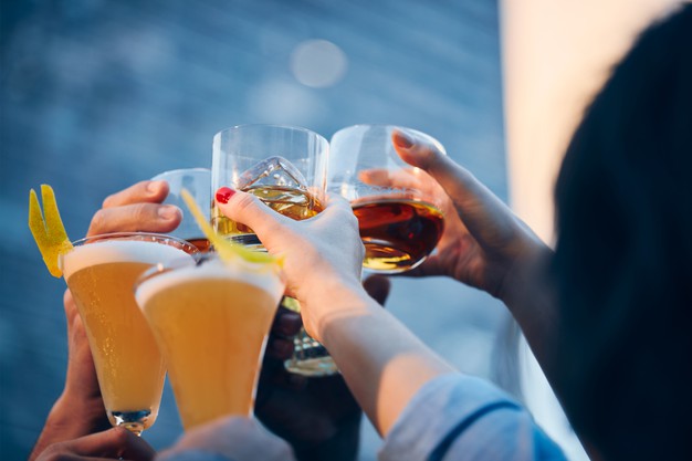 many people clinking glasses with alcohol at a toast