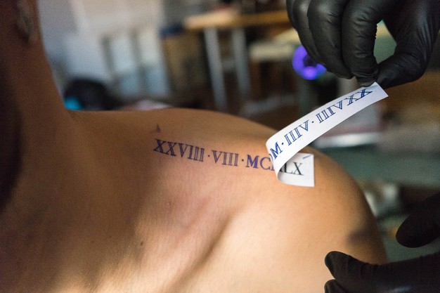 a tattoo artist placing a design on a client's shoulder