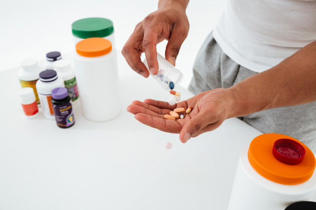 cropped-image-young-sportsman-holding-vitamins-sport-pills