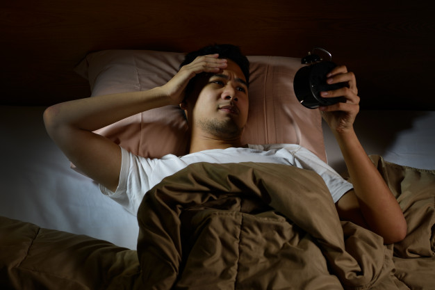 depressed-man-suffering-from-insomnia-looking-alarm-clock-lying-bed