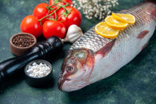 raw fish with tomatoes and lemon on dark blue surface shark seafood meal ocean horizontal dinner food animal water meat