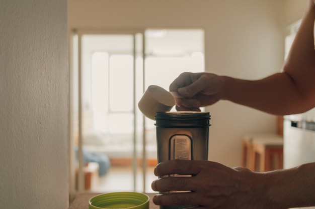 man-put-whey-protein-powder-into-shake-bottle