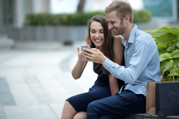 Couple in cafe looking at smartphone screen