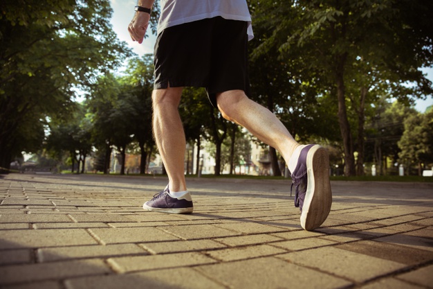Senior man as runner at the city's street. close up shot of legs in sneakers. caucasian male model jogging and cardio training in summer's morning. healthy lifestyle