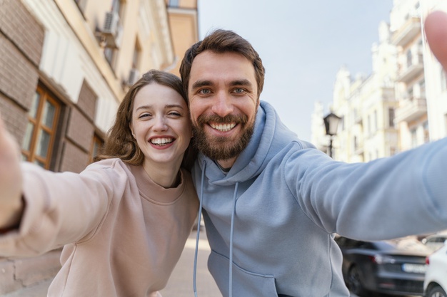 Smiley couple taking a selfie together outdoors in the city 