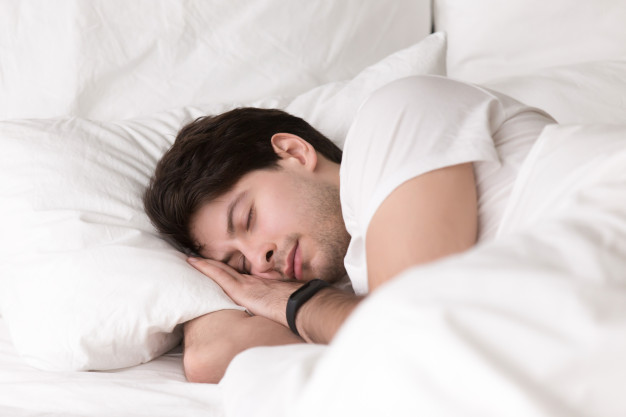  guy sleeping in bed wearing smartwatch or sleep tracker