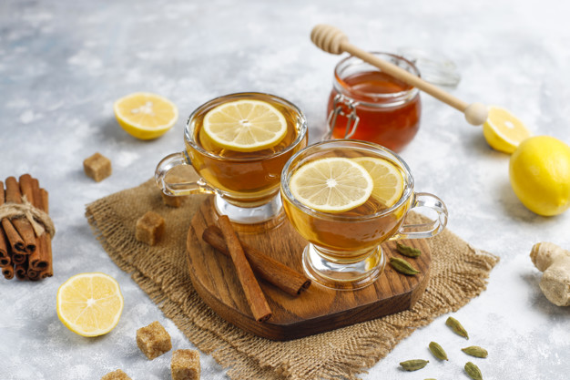 A cup of tea,brown sugar,honey and lemon on concrete