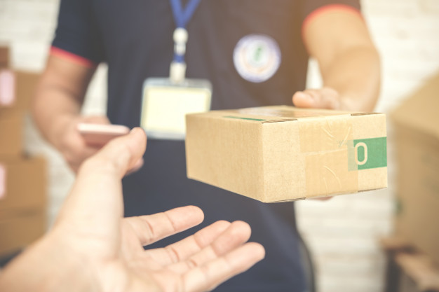 Delivery man smiling and holding a cardboard box