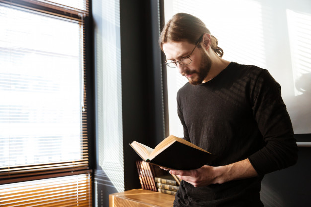 Handsome young man in office working while reading book