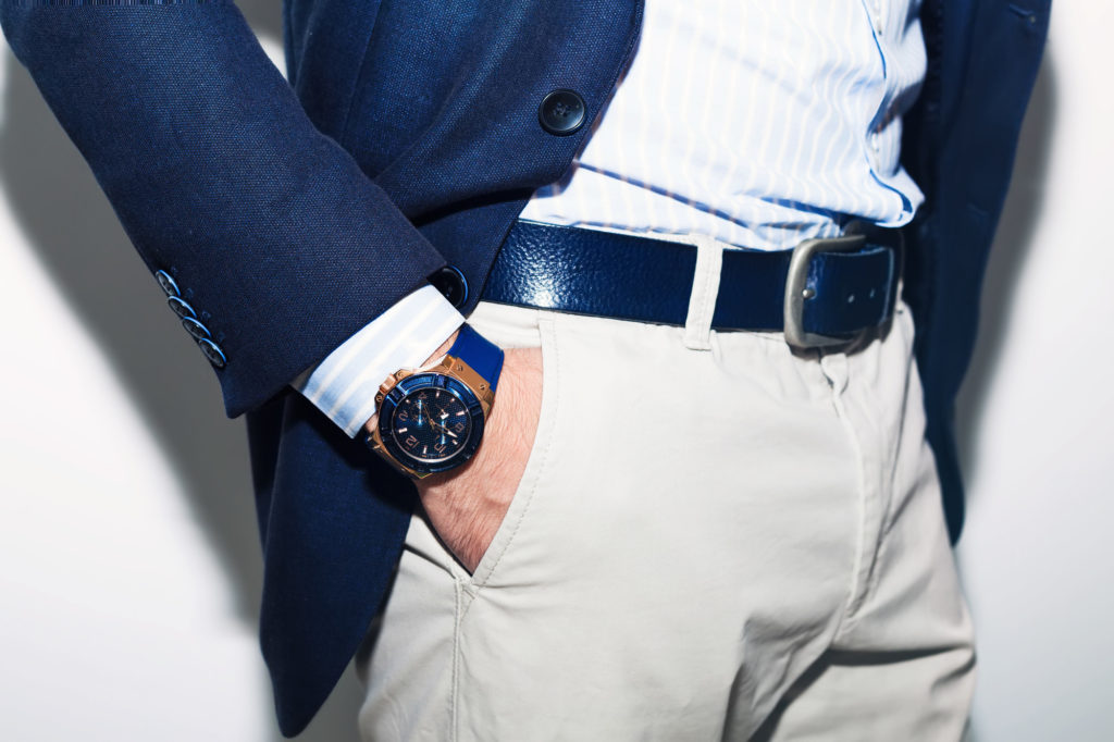 Closeup fashion image of luxury watch on wrist of man.body detail of a business man.Man's hand in a white shirt and blue jacket in a pants pocket closeup