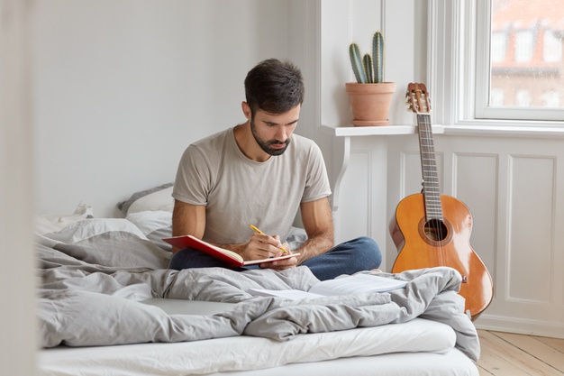 man with dark bristle, writes down story in diary about what happened during day