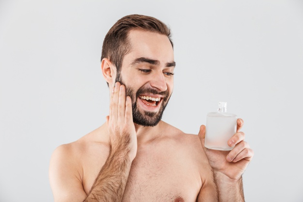portrait-cheerful-shirtless-bearded-man-applying-aftershave-lotion-isolated-white