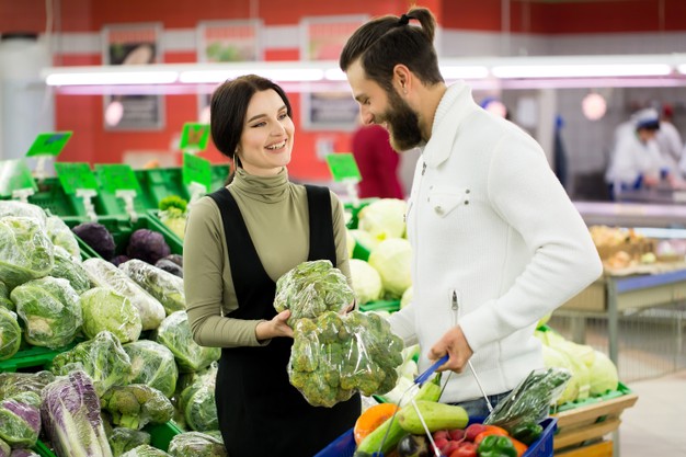 healthy couple looking at fruits and vegetables in the supermarket while shopping