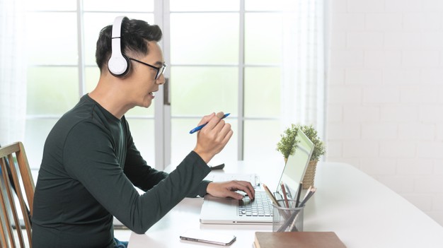 handsome asian businessman wear headphones working remotely from home.