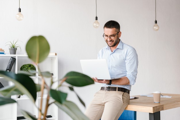 smiling-satisfied-man-30s-wearing-white-shirt-sitting-table-office-having-business-chat-silver-laptop